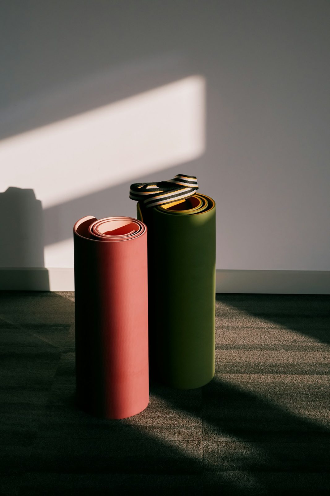 Two rolled yoga mats in a ray of sunlight